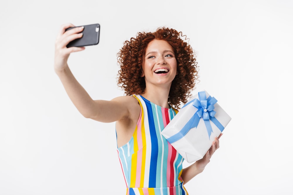 a woman holding a gift and a cell phone
