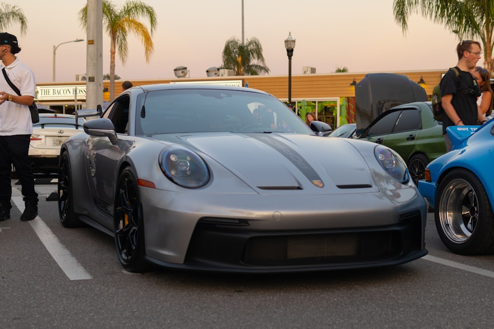 a man standing next to a silver sports car