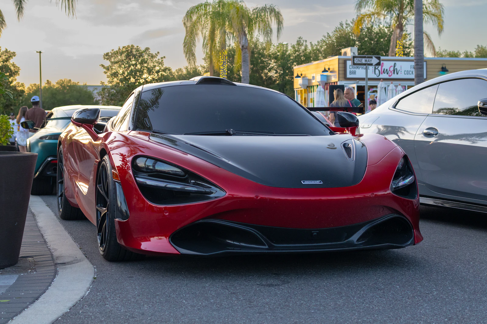 Red McLaren with a carbon fiber hood at an outdoor car meet