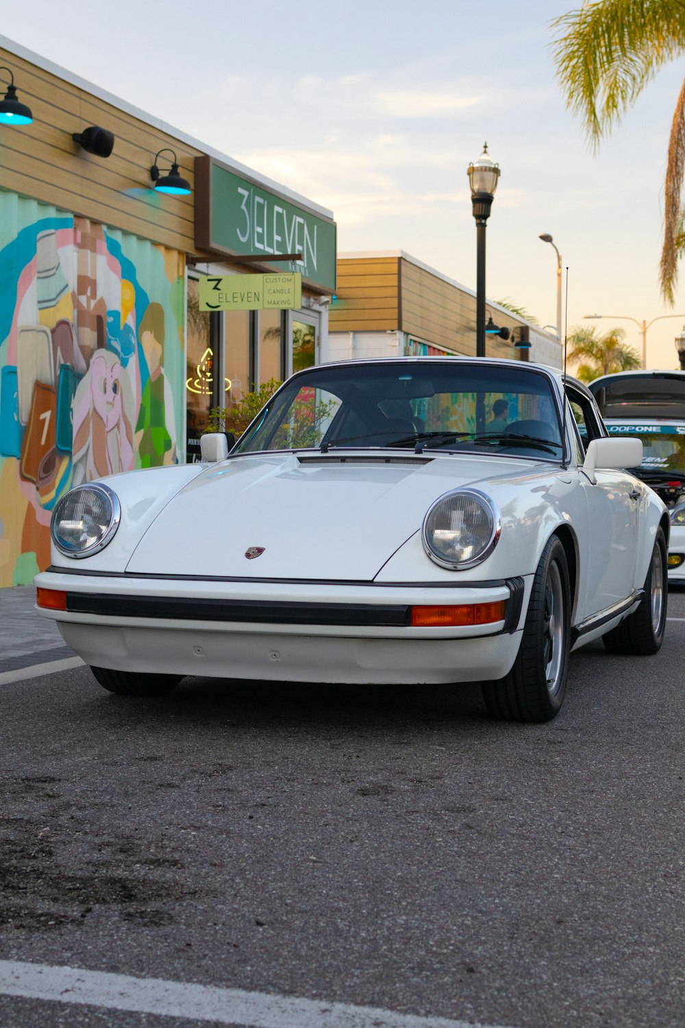 a white porsche parked in front of a store