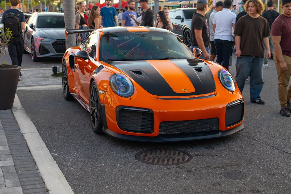 an orange and black sports car parked on the side of the road