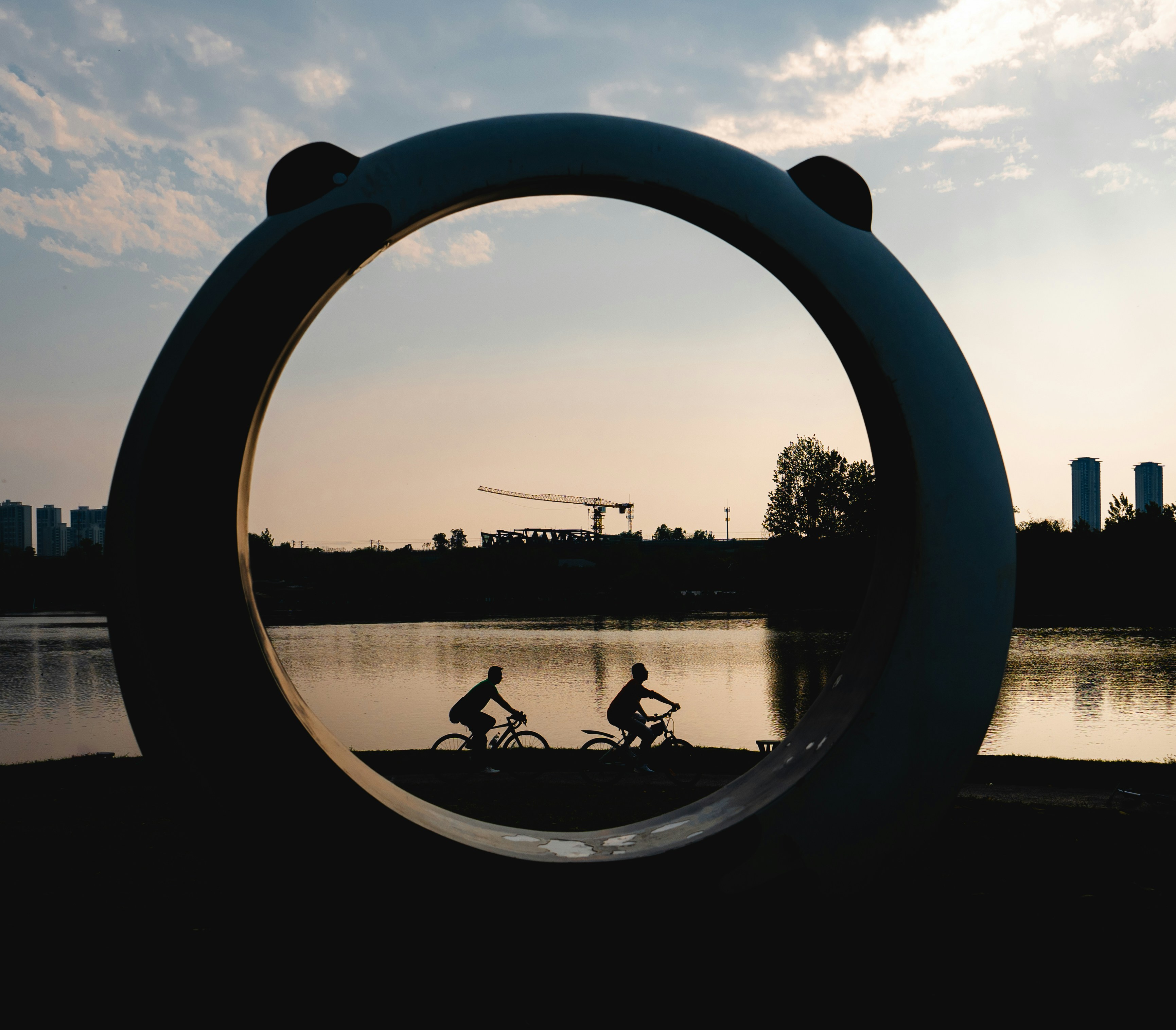 a couple of people riding bikes next to a body of water