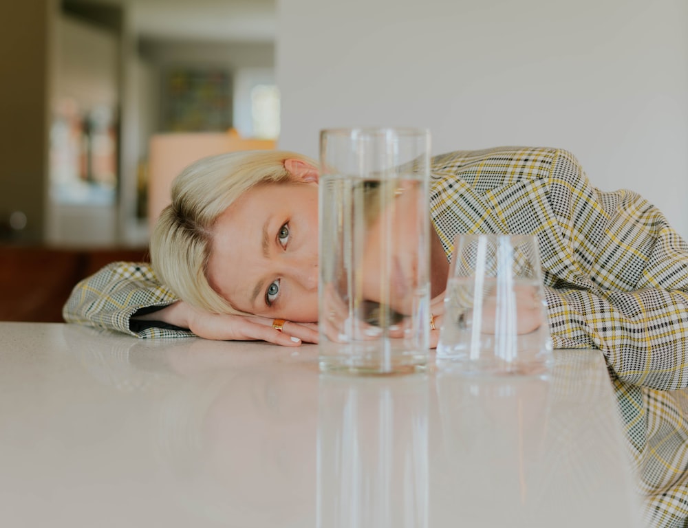 a woman leaning her head on a table with glasses