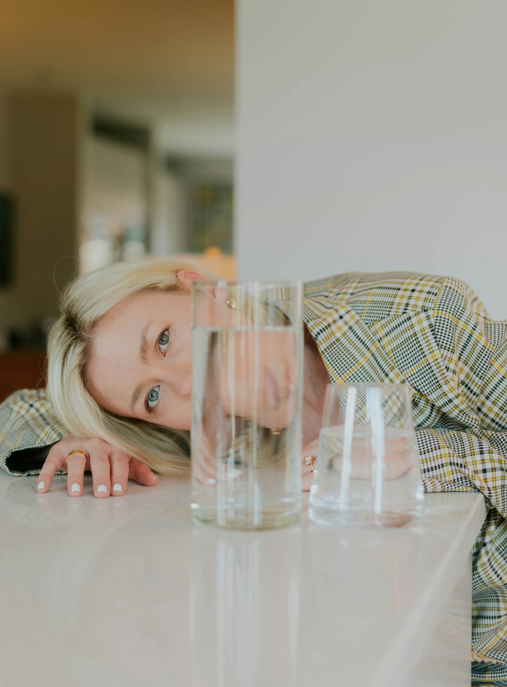 a woman leaning on a table with a glass of water in front of her