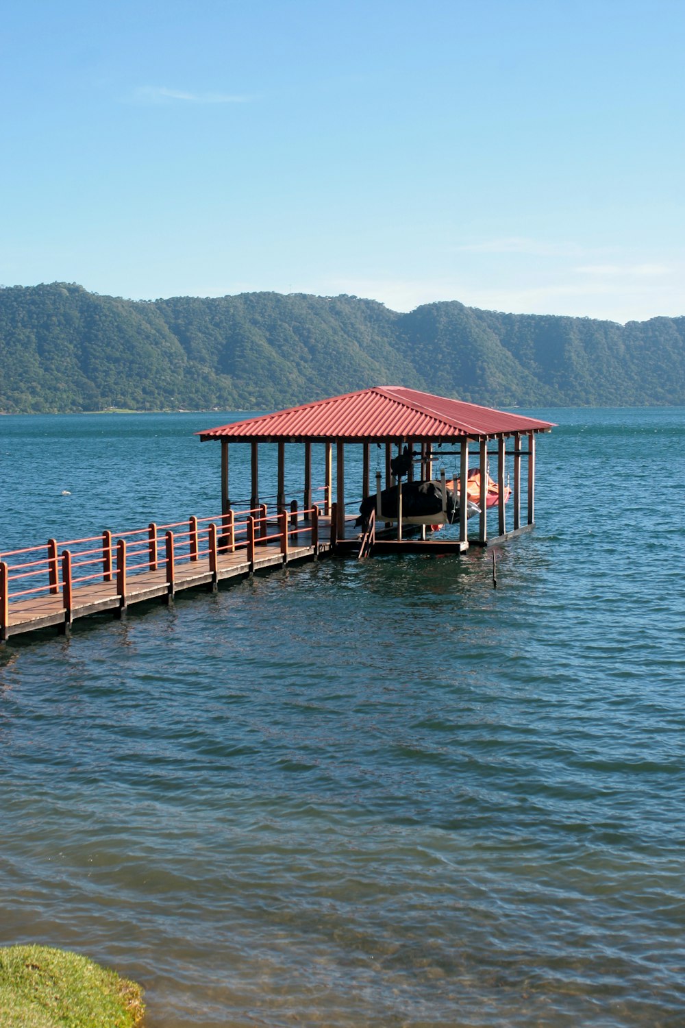 a boat dock with a red roof on a lake
