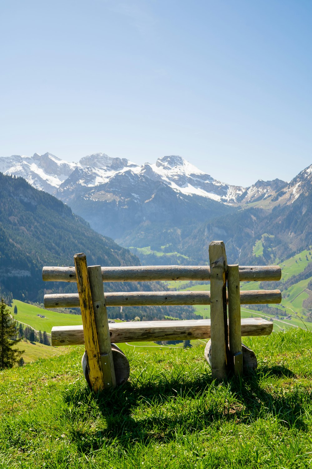 a wooden bench sitting on top of a lush green hillside