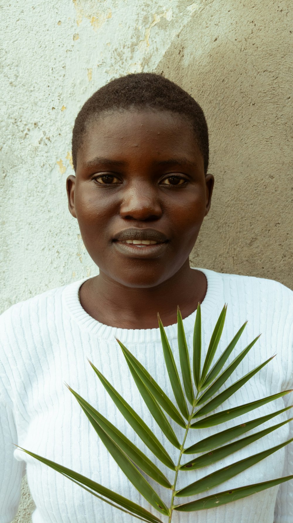 a woman holding a palm leaf in front of her face