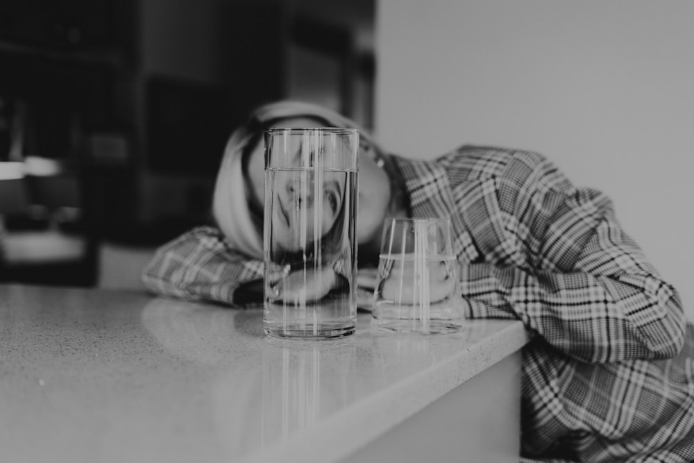 a man leaning his head on a counter next to a glass