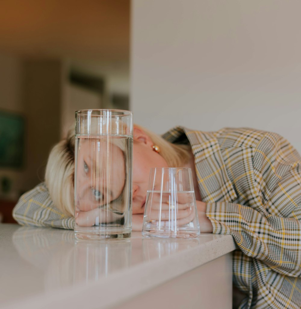 a woman leaning on a counter next to a glass of water