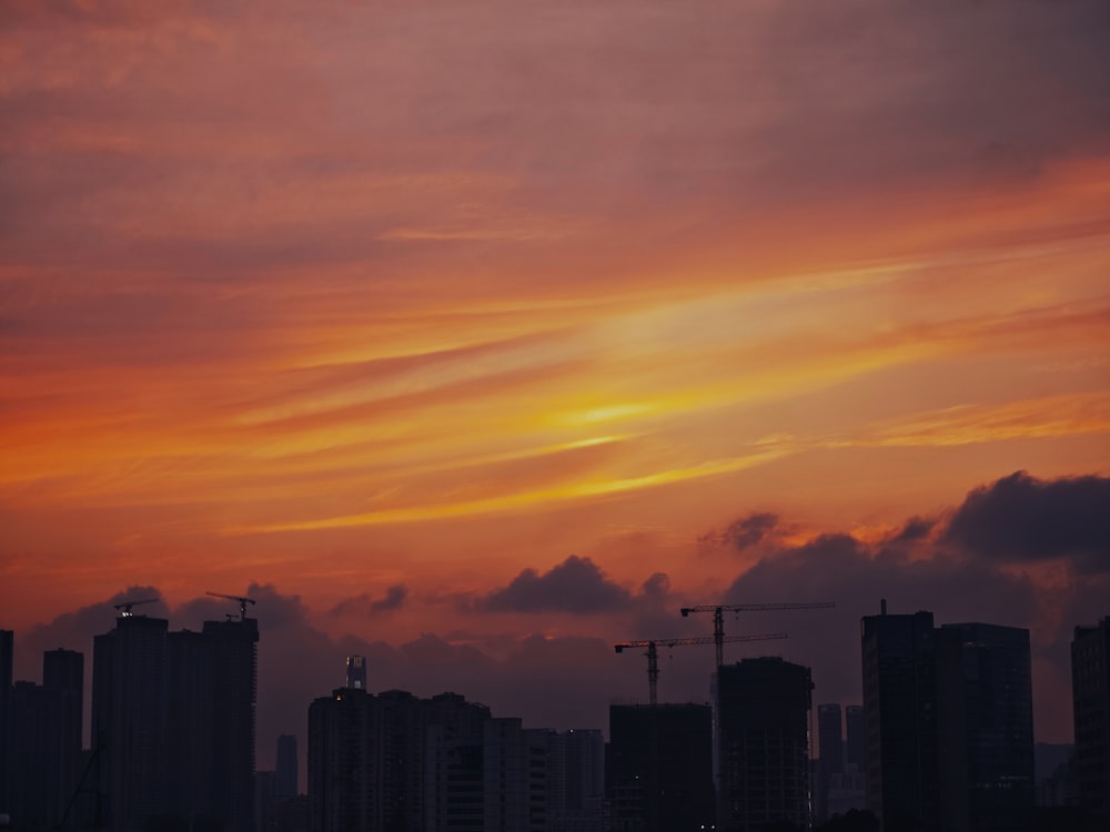 a sunset view of a city with a crane in the foreground