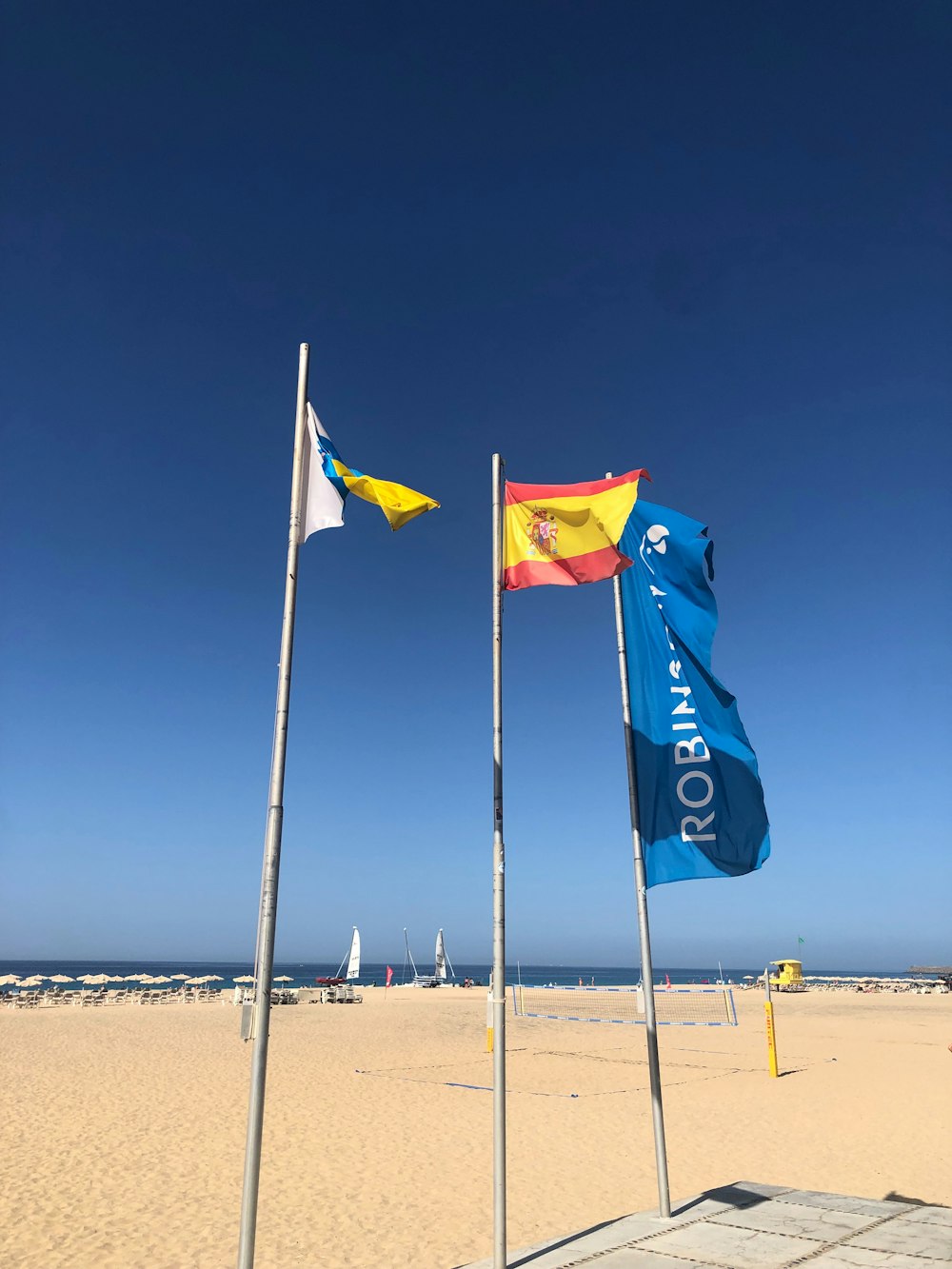 a sandy beach with a few flags flying in the wind