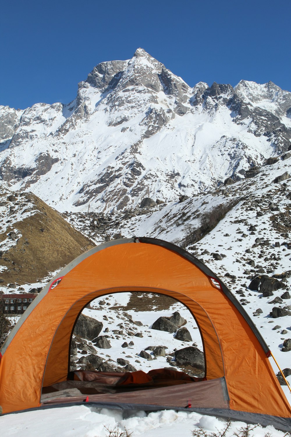 a tent pitched up in the snow with a mountain in the background