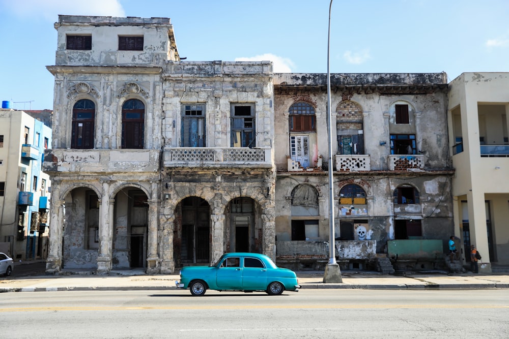 a blue car parked in front of an old building