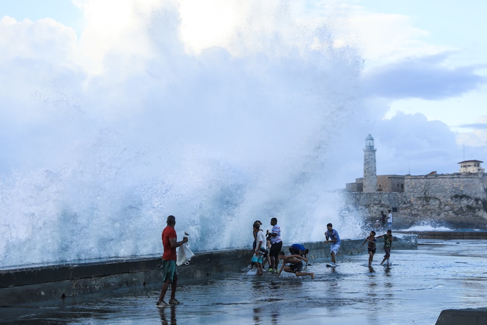 a group of people standing next to a large wave