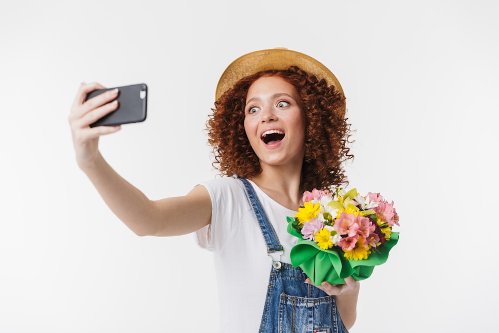 a woman holding a bouquet of flowers taking a selfie