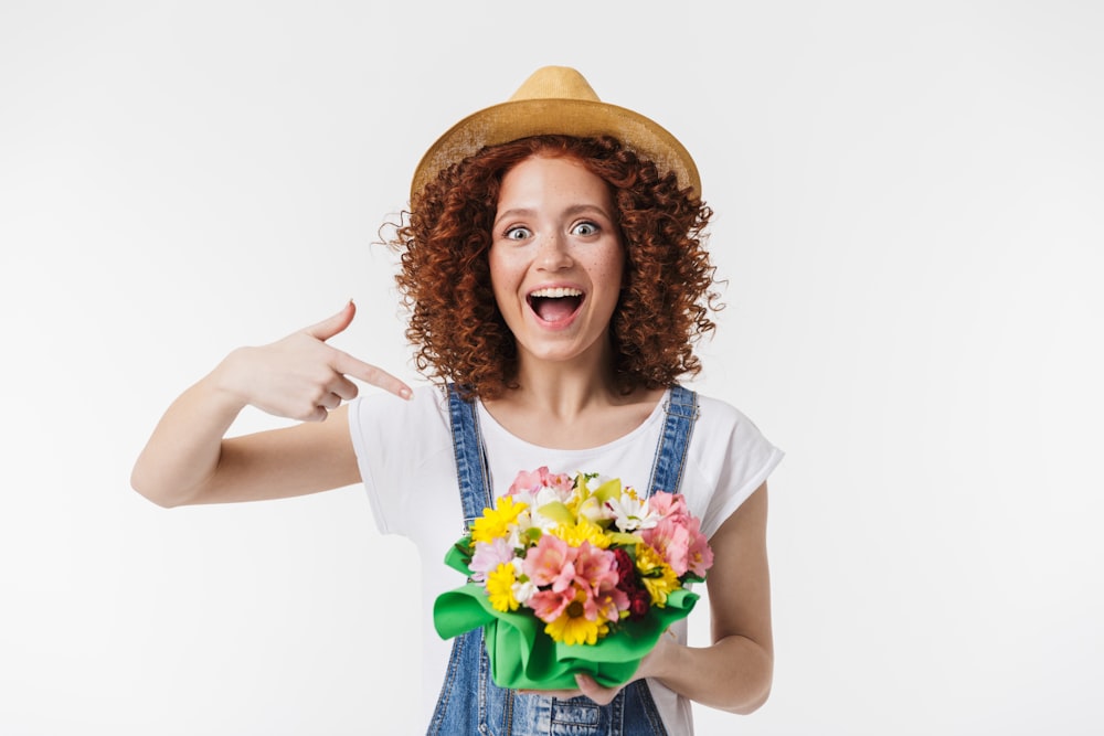 a woman in overalls holding a bouquet of flowers