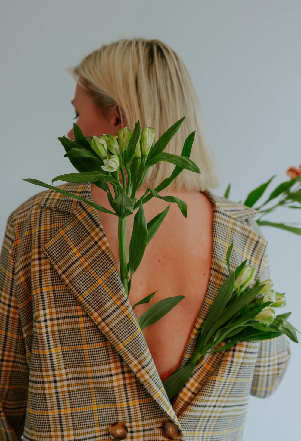a woman wearing a plaid blazer with flowers in her hair