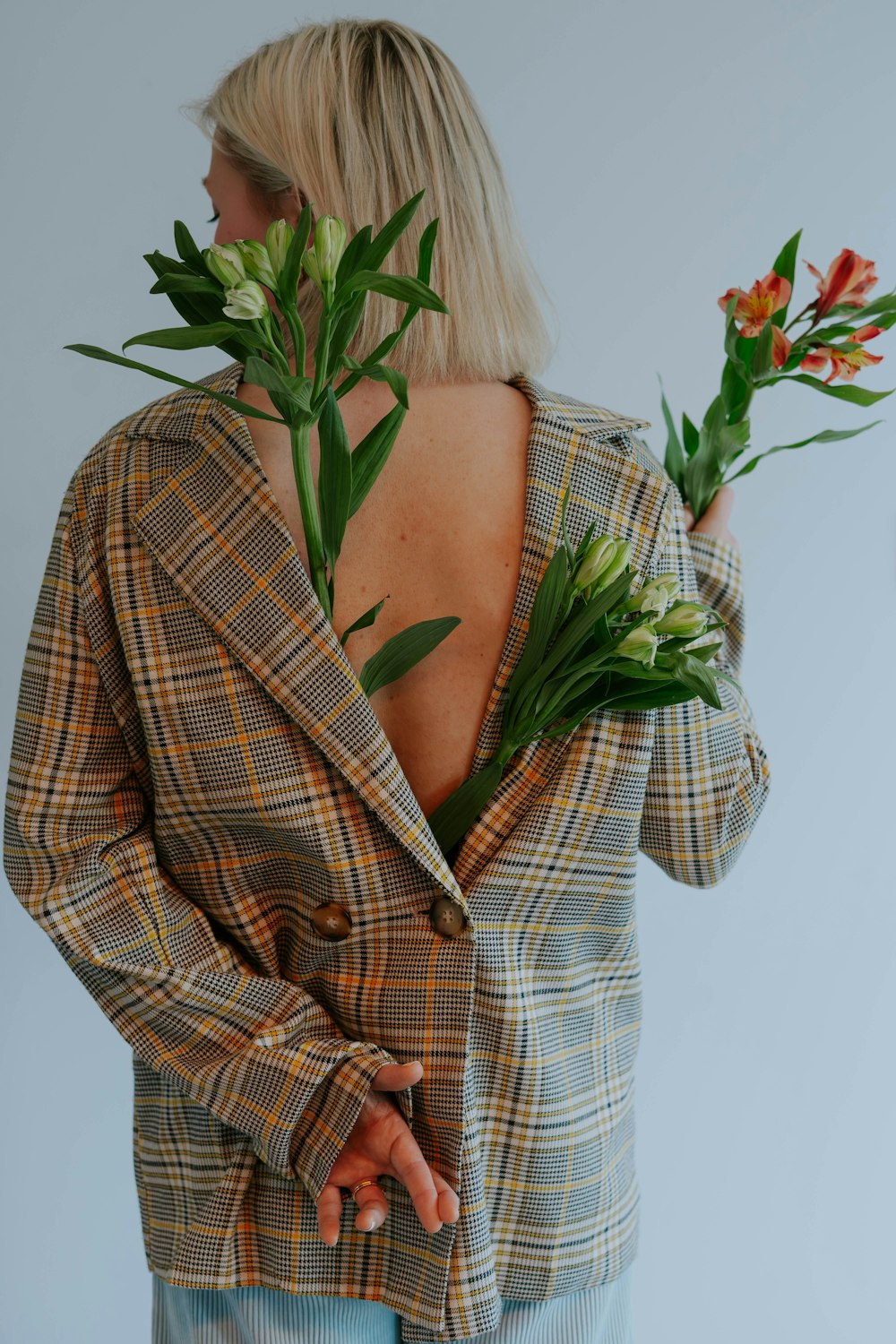 a woman wearing a plaid jacket holding flowers