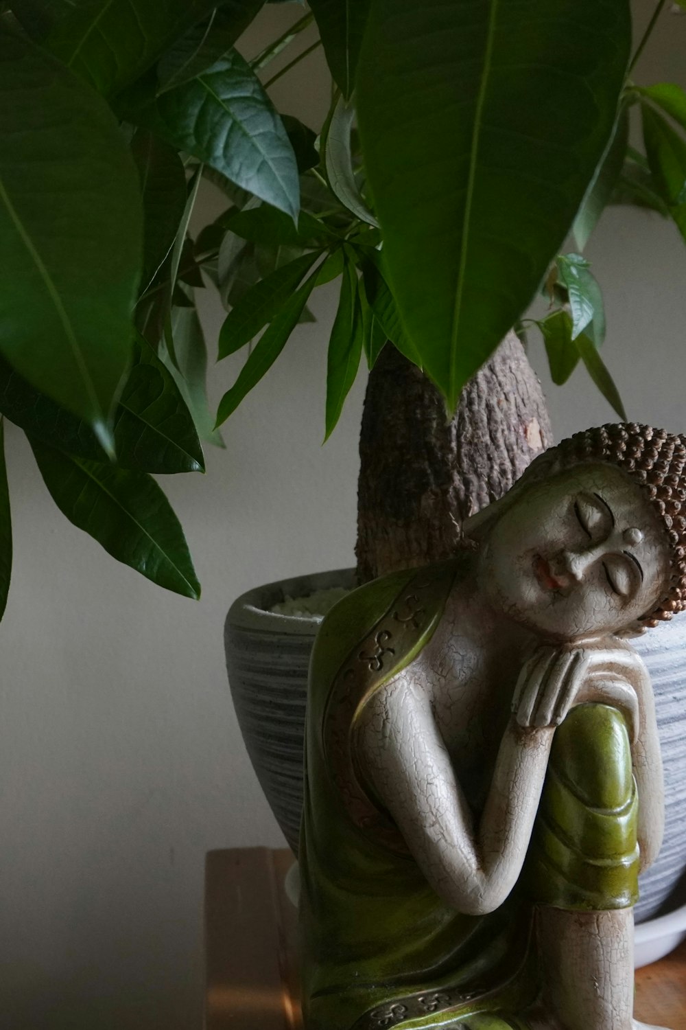 a buddha statue sitting next to a potted plant