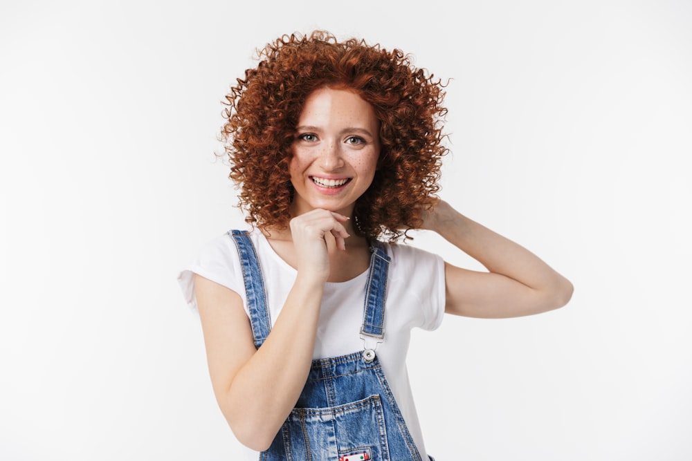 a woman with red curly hair wearing overalls