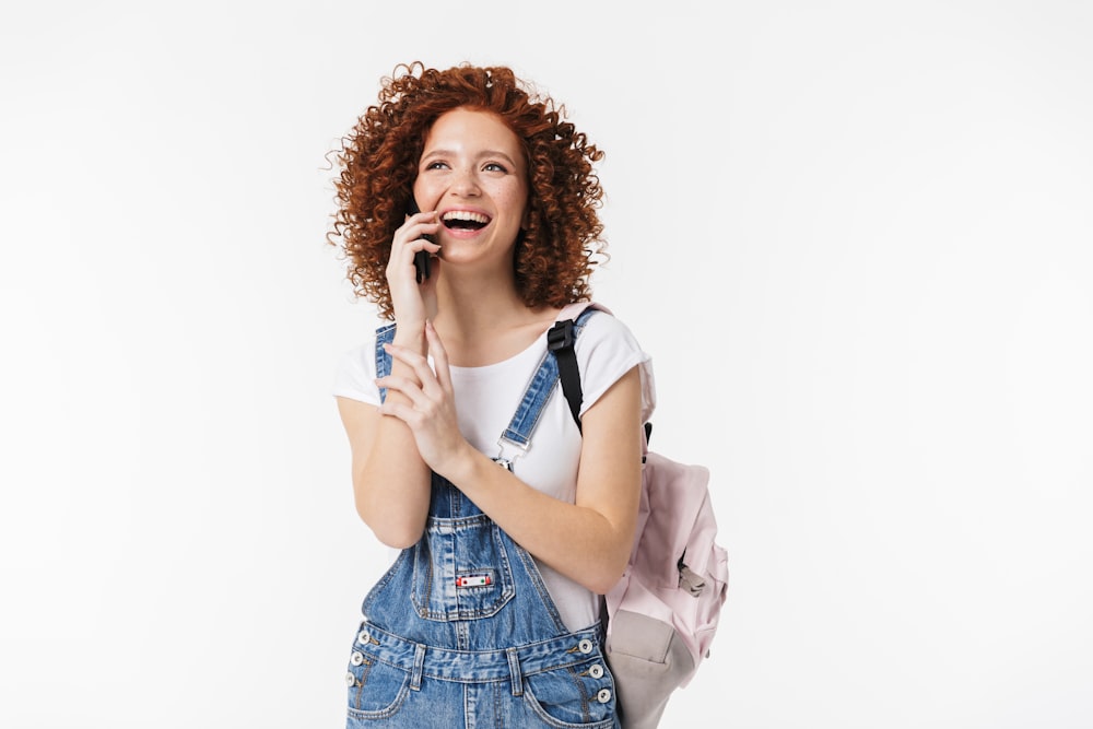 a woman with curly hair is holding a pink bag