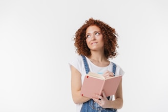 a woman with curly hair is holding a book