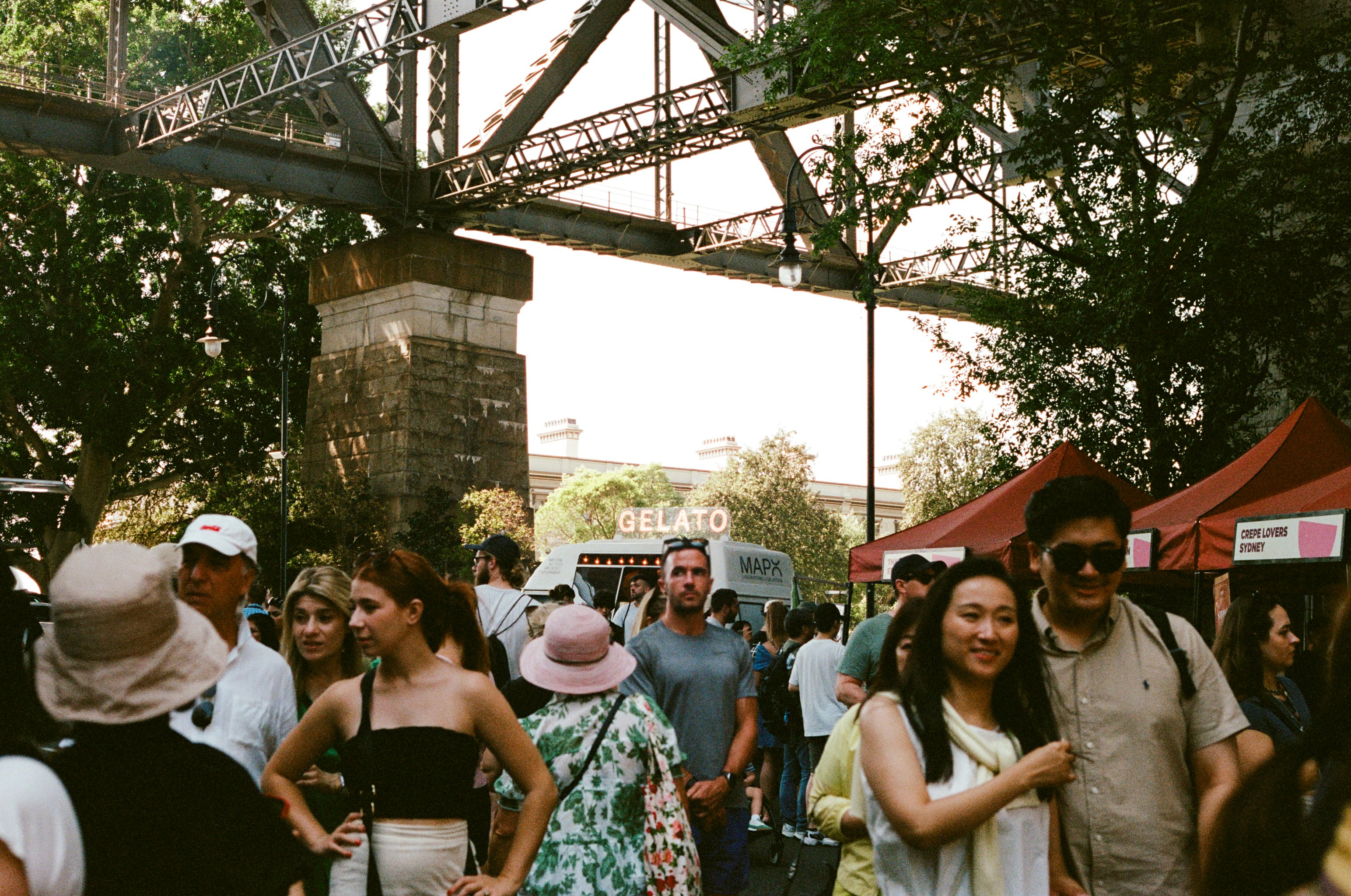a crowd of people walking under a bridge