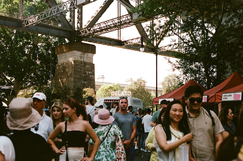 a crowd of people walking under a bridge