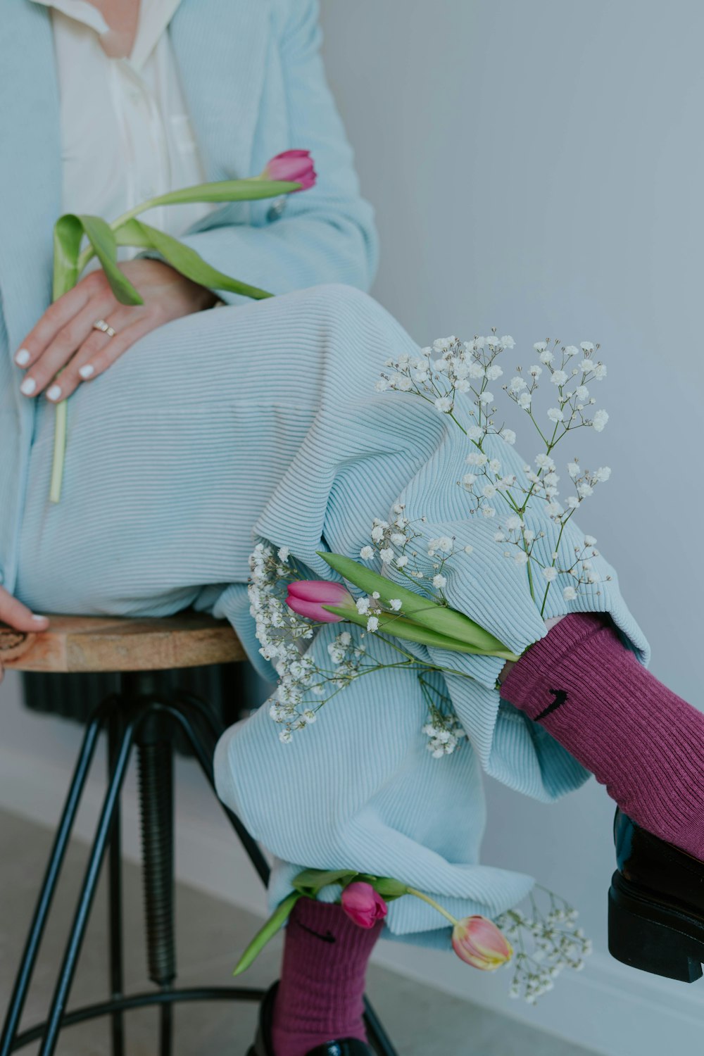 a woman sitting on a stool holding a bouquet of flowers