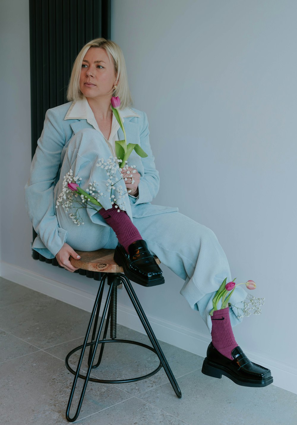 a woman sitting on a stool holding a flower