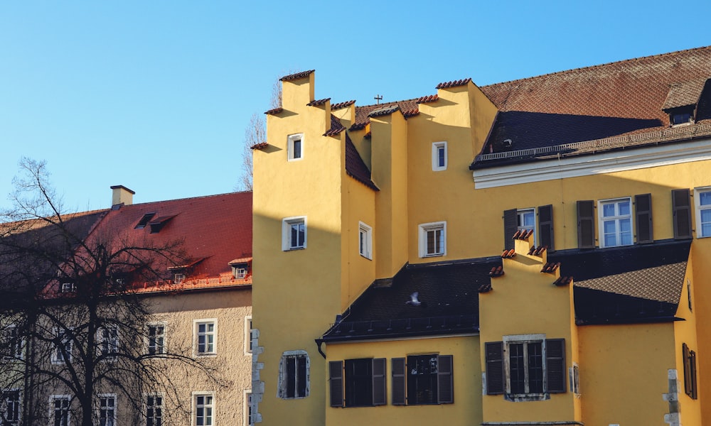 a large yellow building with black roof and windows