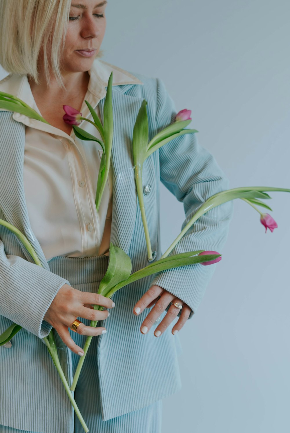 a woman in a blue suit holding a bunch of flowers