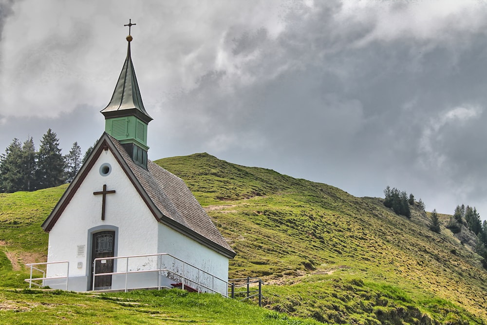 a white church with a green steeple on a hill