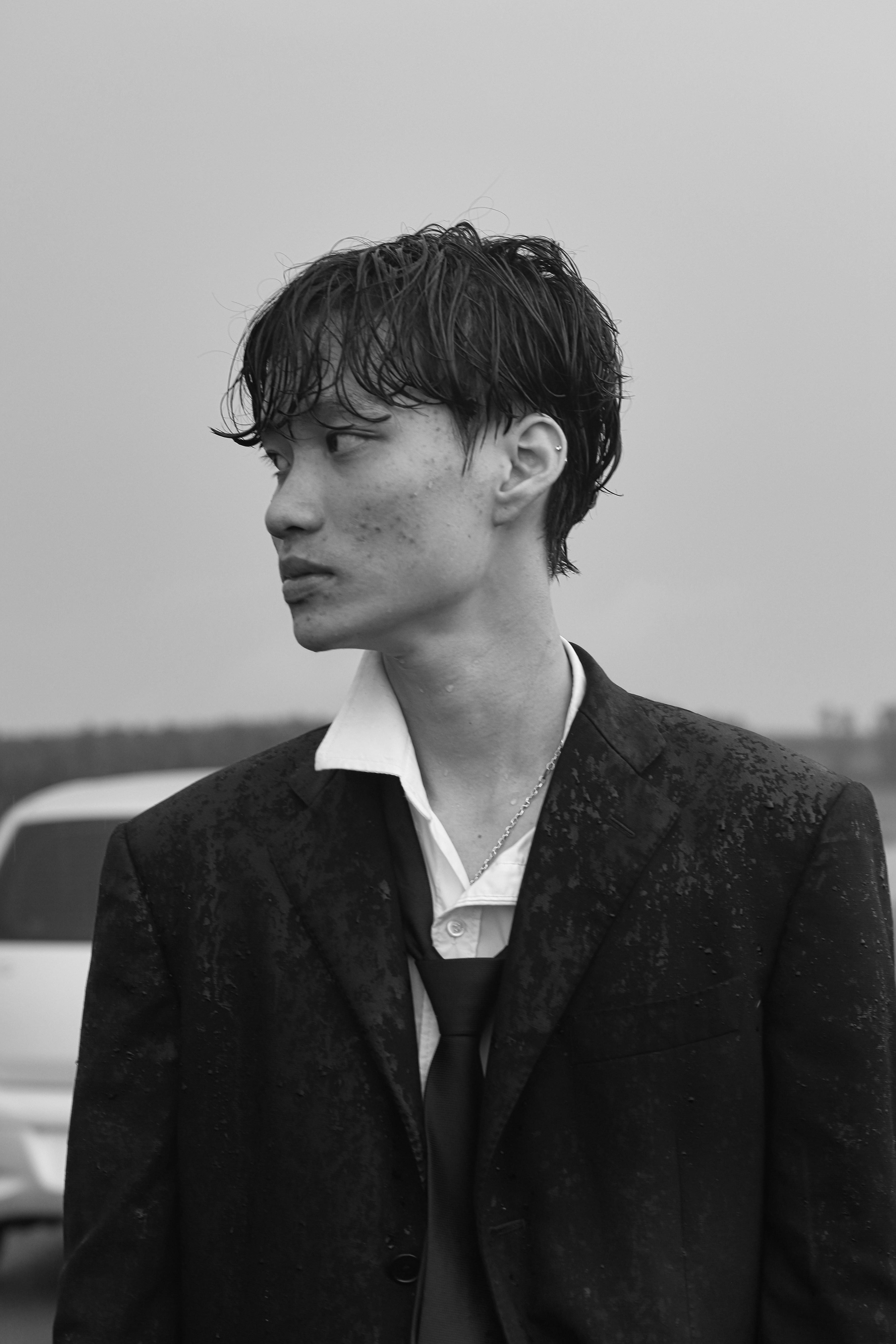 a man in a suit and tie standing in front of a car