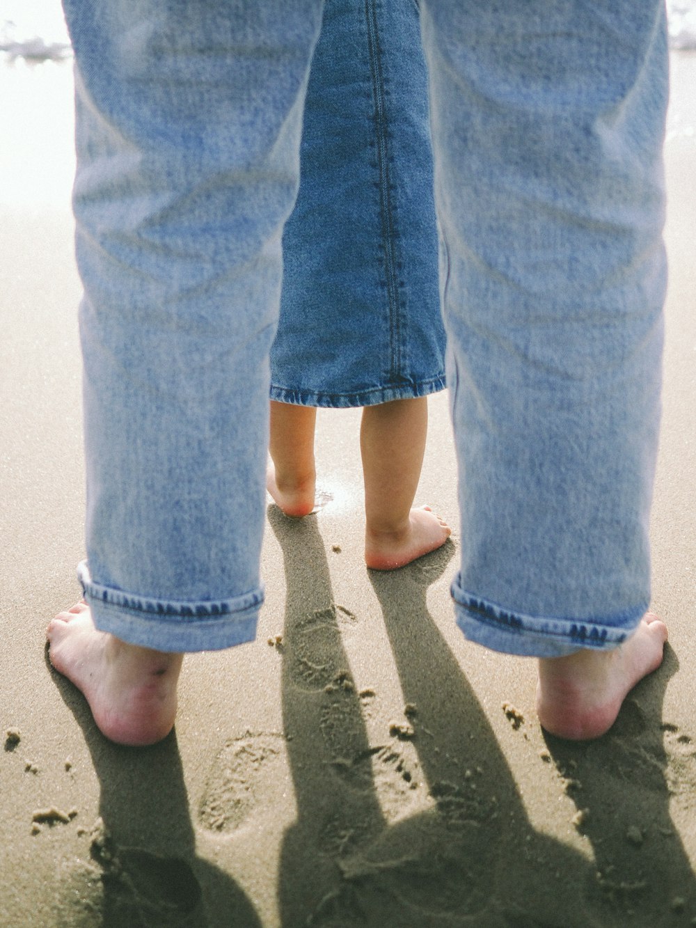 two people standing in the sand on the beach