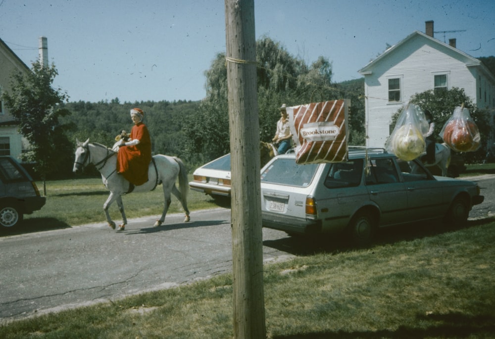 a man riding a horse down a street next to a car