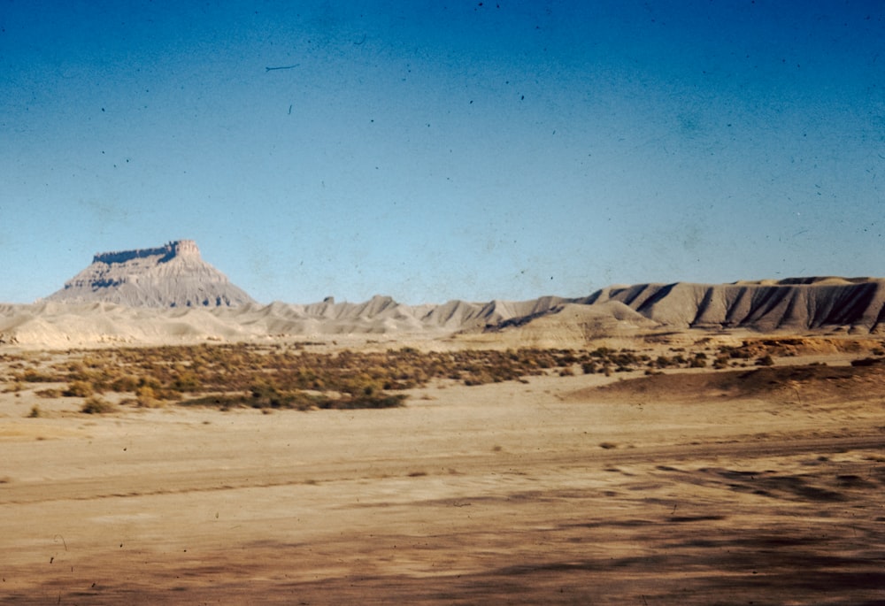 a desert landscape with a mountain in the distance