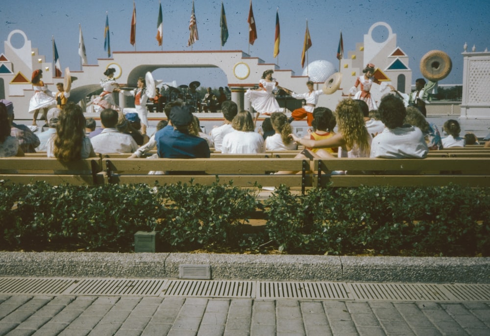 un grupo de personas sentadas encima de un banco de madera