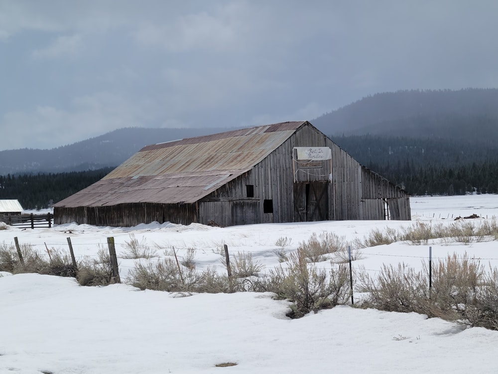 a barn in the middle of a snowy field