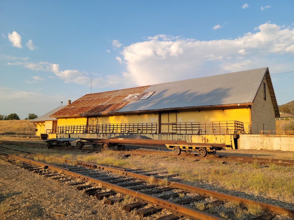 Un edificio amarillo sentado al costado de una vía de tren