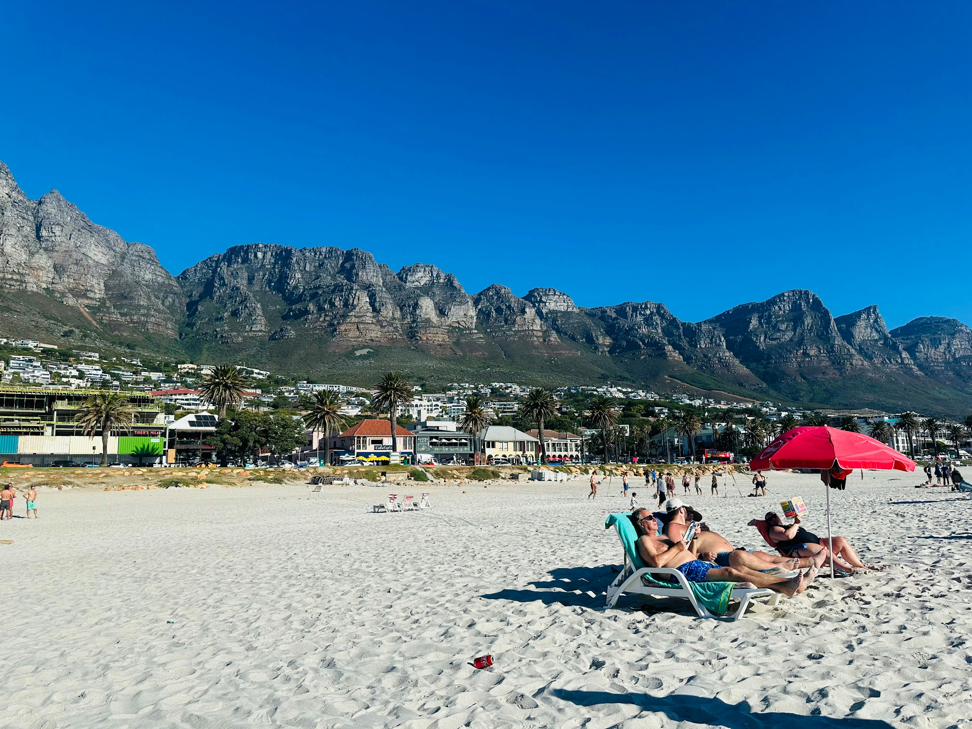 a group of people sitting on top of a sandy beach