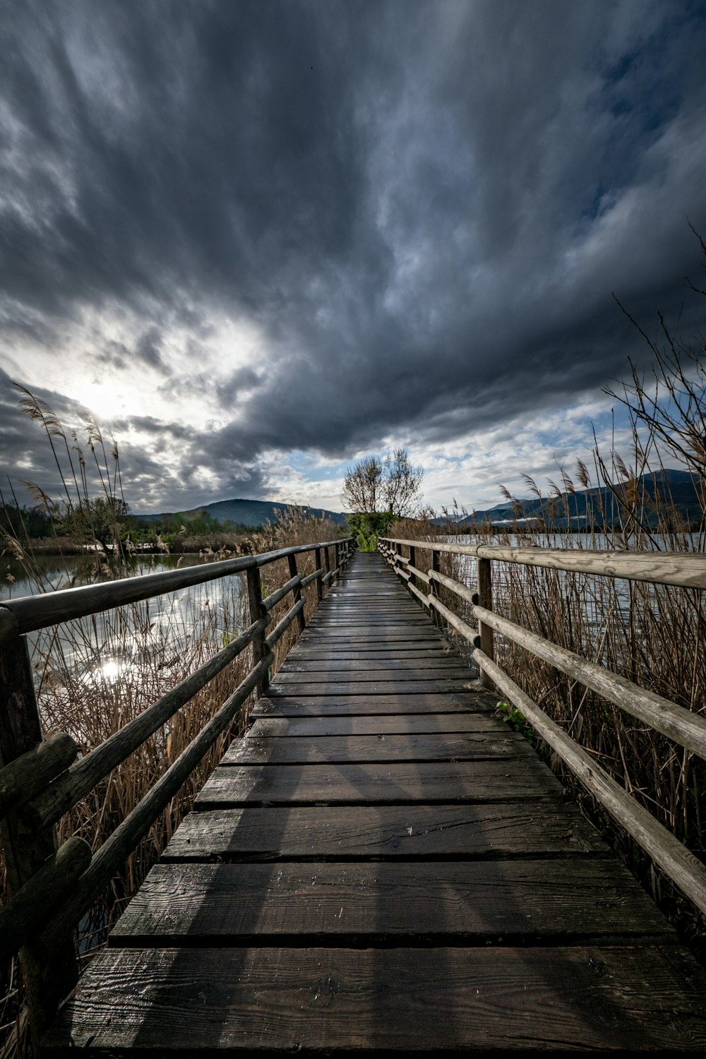 a wooden bridge with a cloudy sky in the background