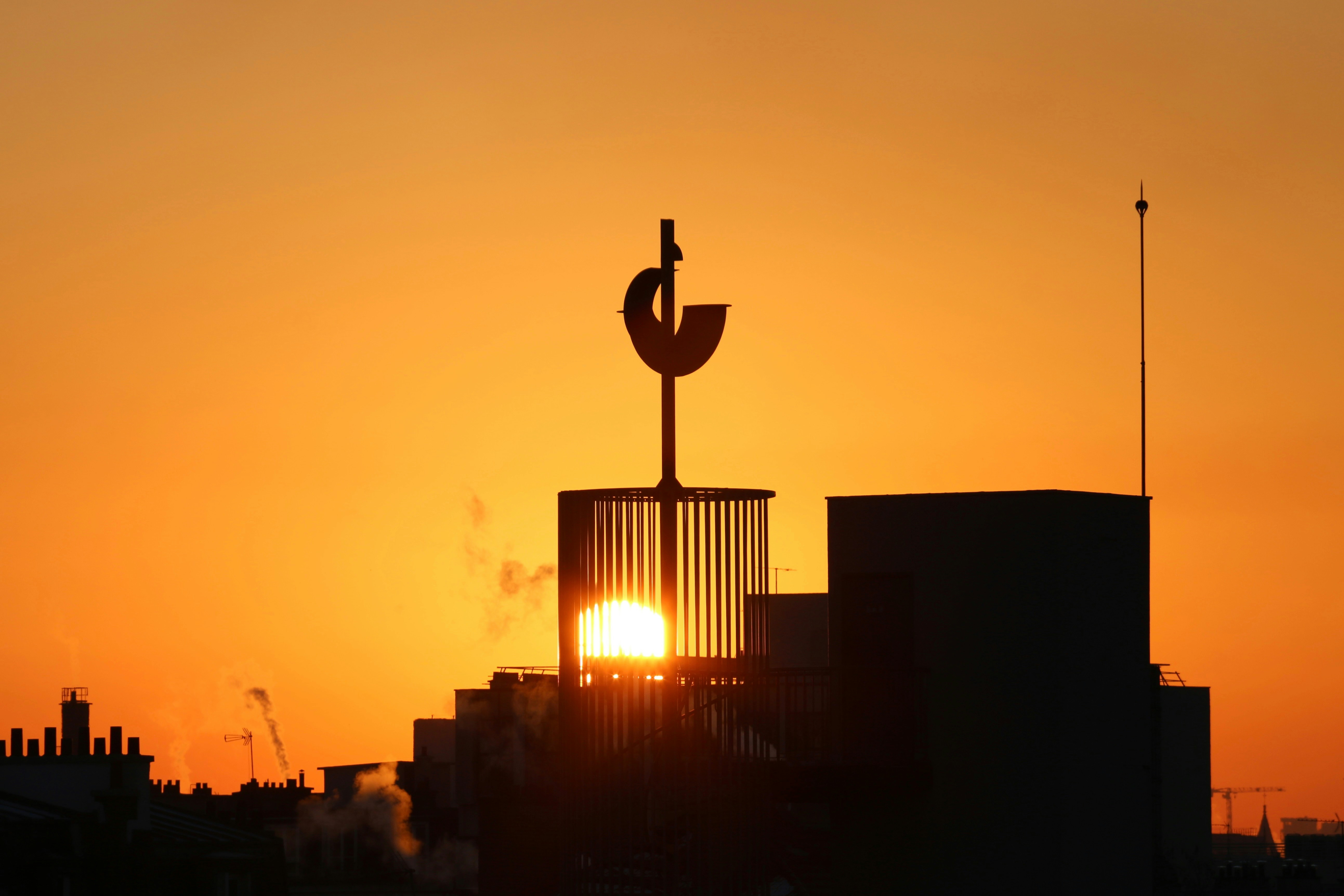 the sun is setting behind a tall building