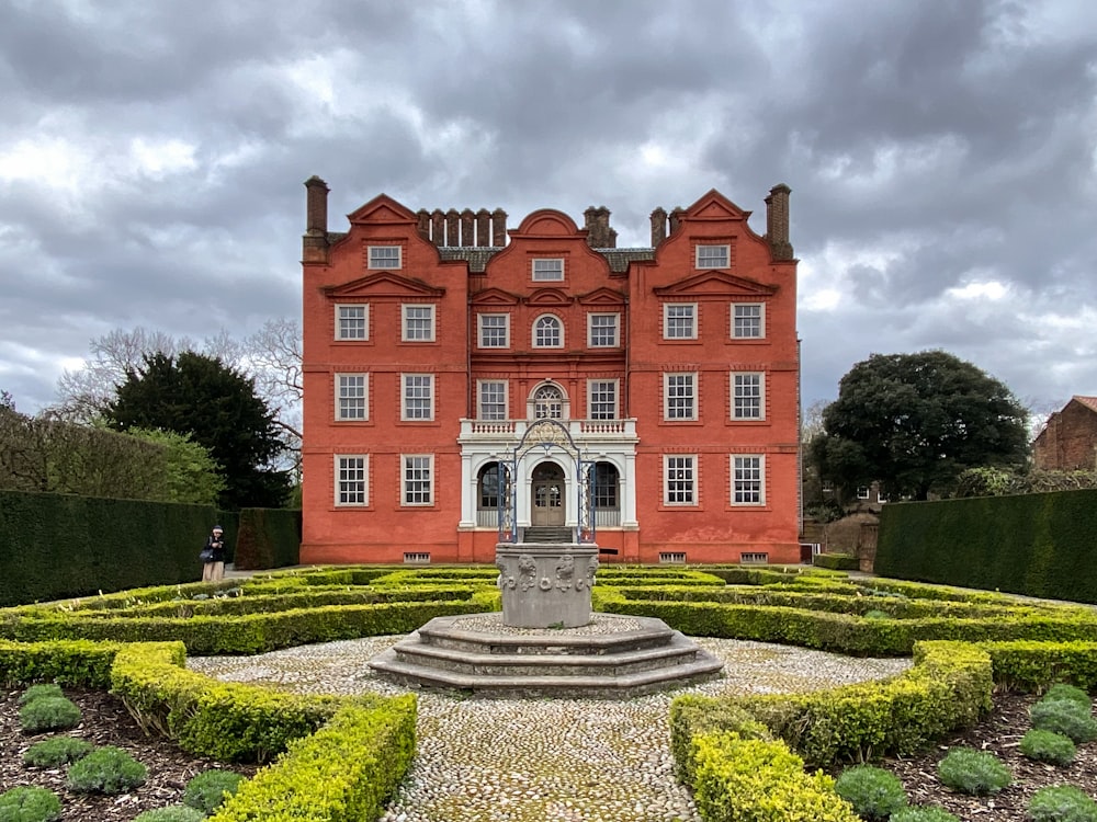 un grande edificio rosso con un giardino di fronte