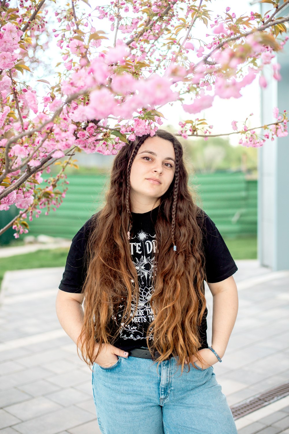 a woman with long hair standing in front of a tree