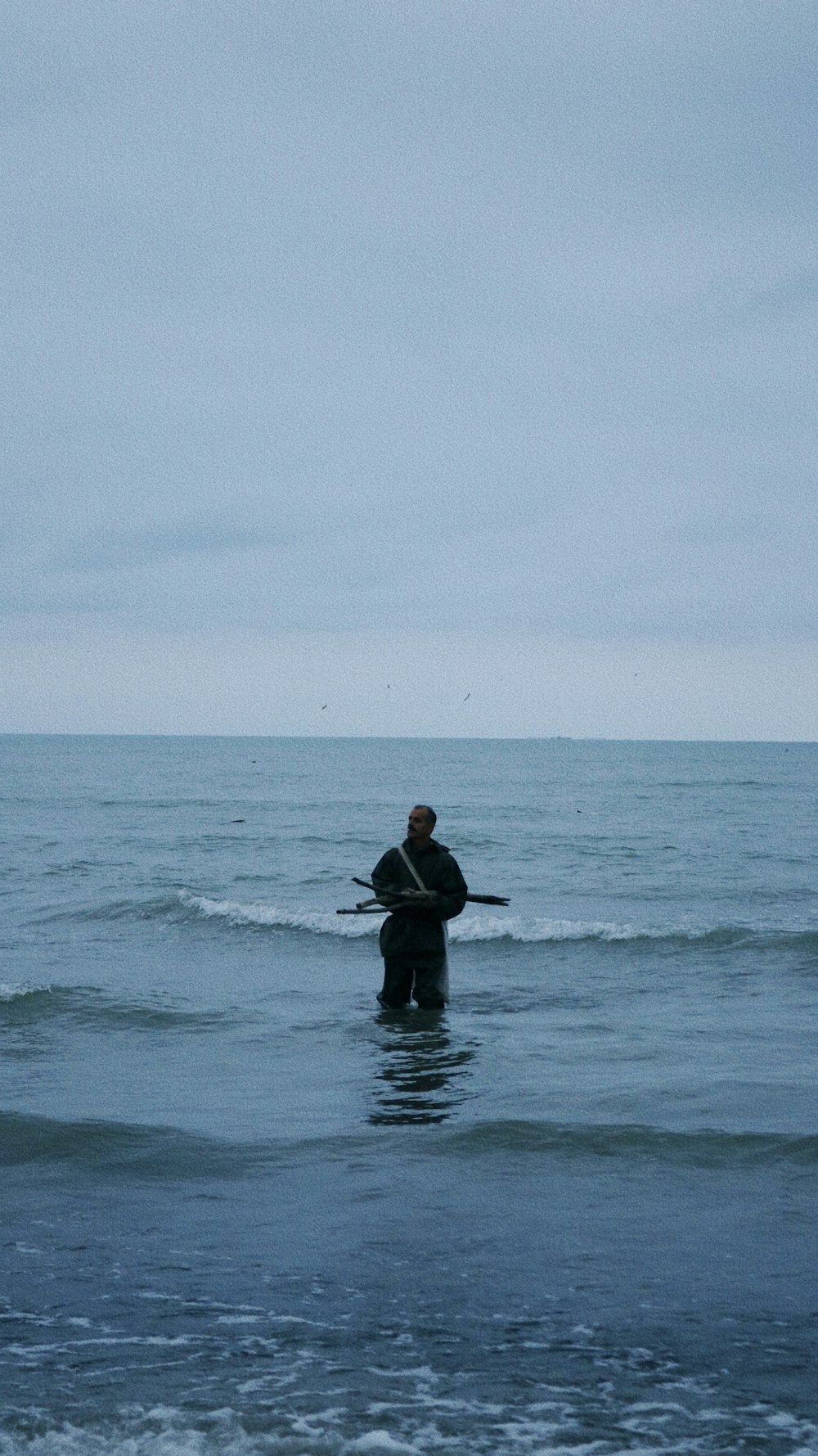 a man standing in the ocean holding a surfboard