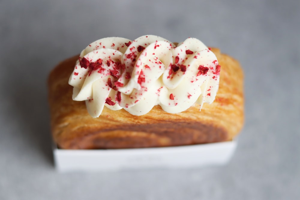 a pastry with white icing and red sprinkles