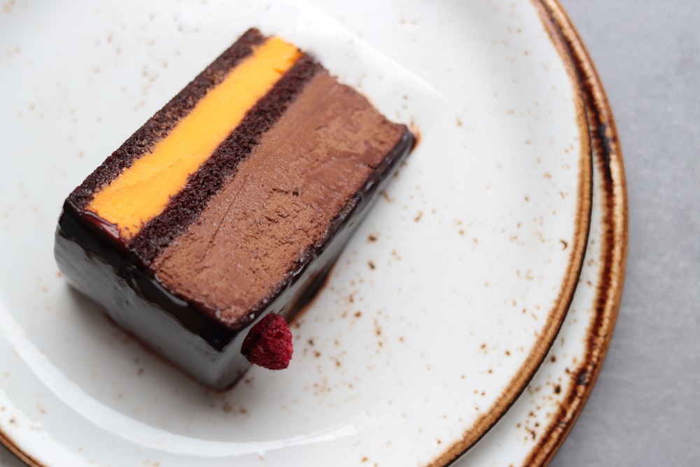 un morceau de gâteau au chocolat avec des framboises sur une assiette