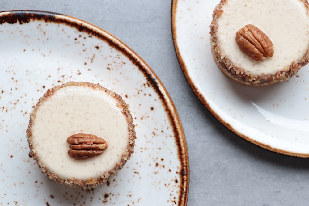 two desserts on plates with pecans on top of them