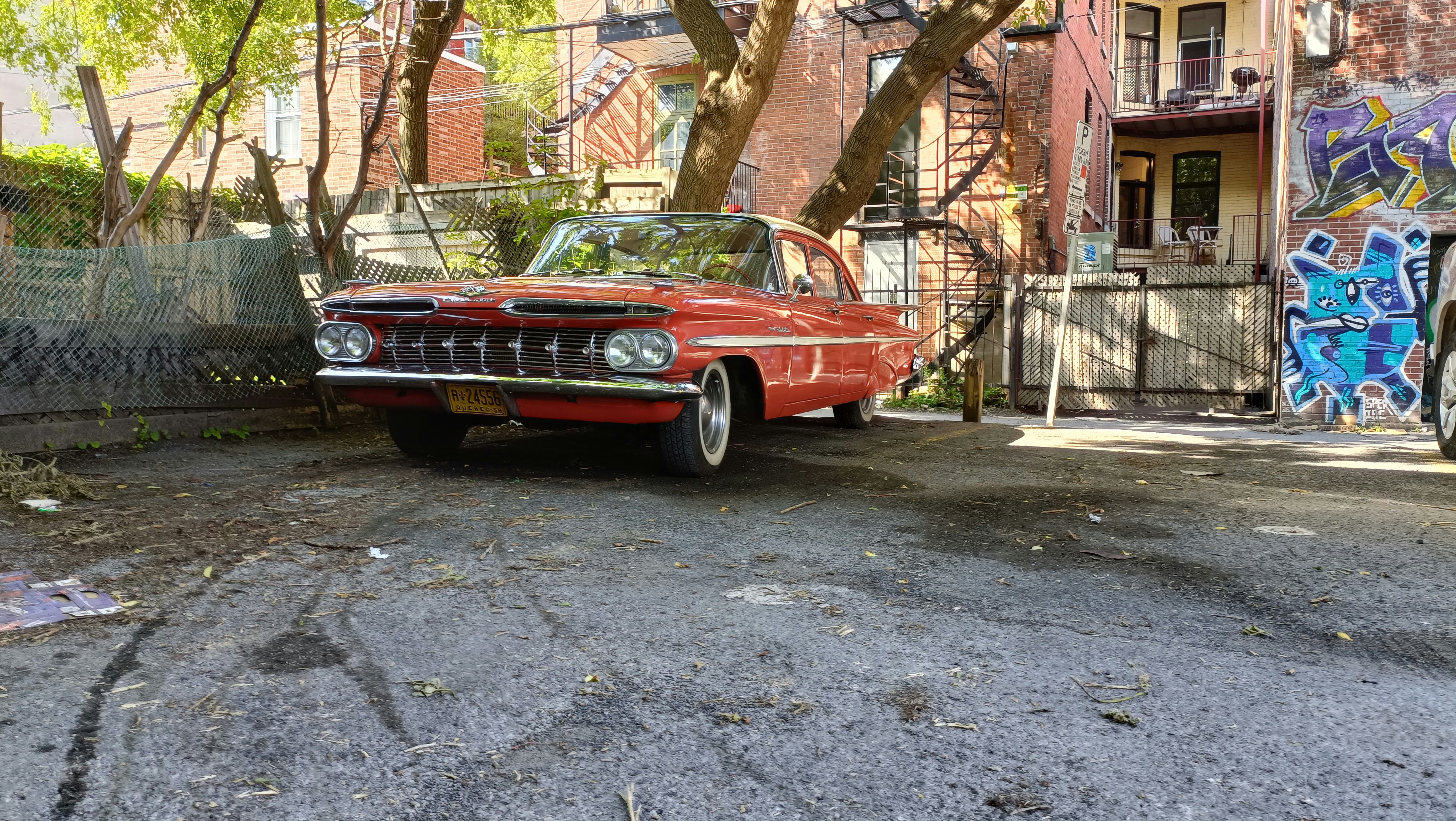 an old red car parked in front of a building